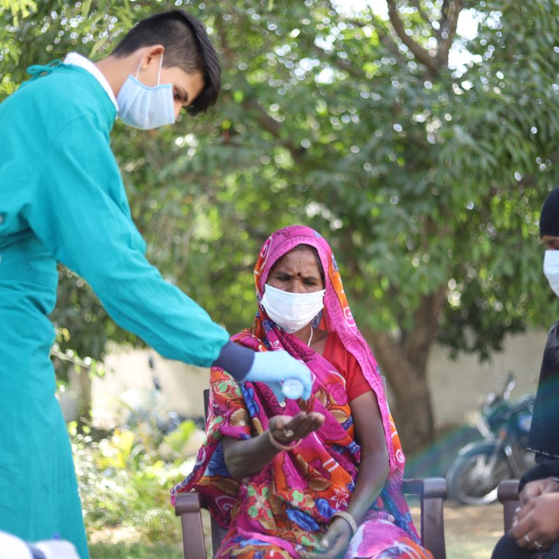 A closeup shot of doctors and patients with masks sitting on the park